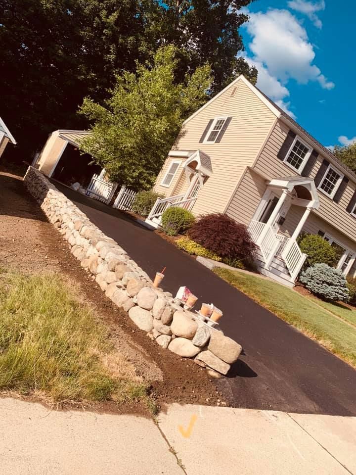 A house with a driveway and a stone wall in front of it.