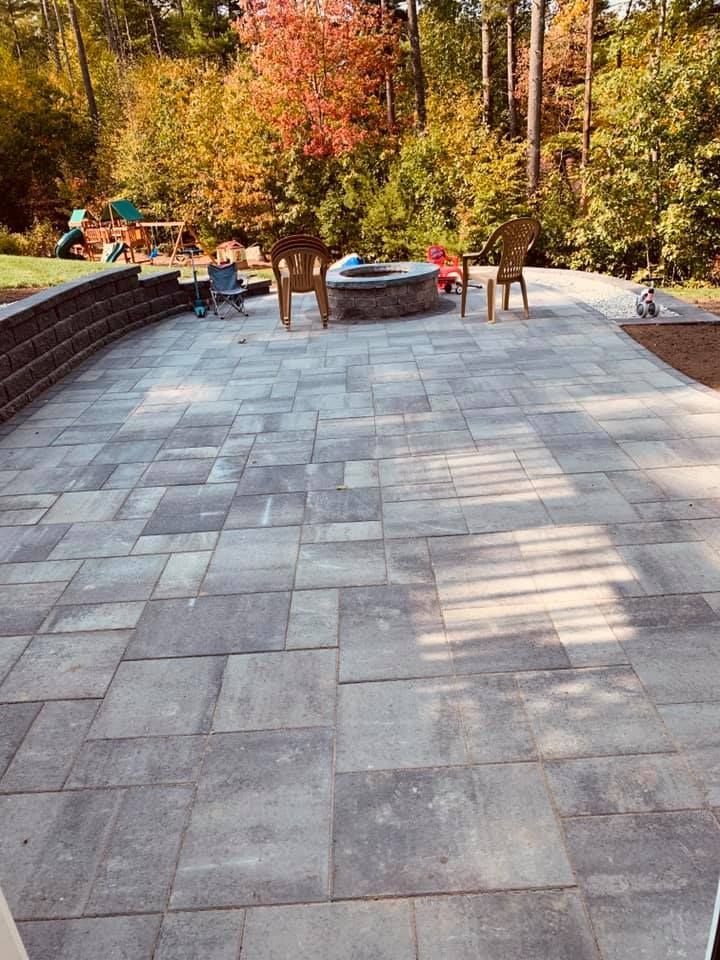 A patio with chairs and a fire pit in the middle of it.