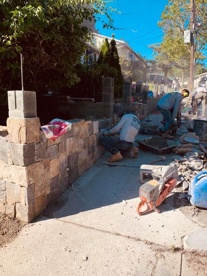 A group of men are working on a brick wall.