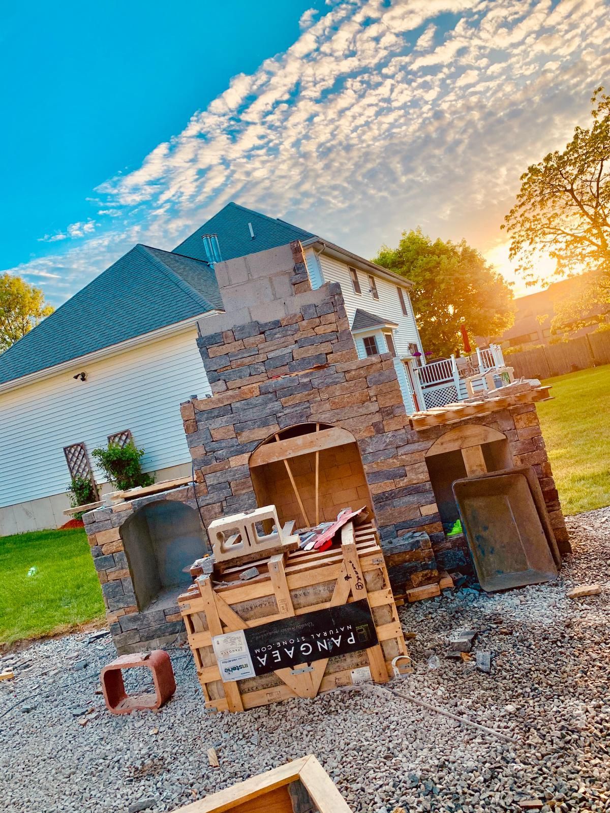 A brick fireplace is being built in the backyard of a house.