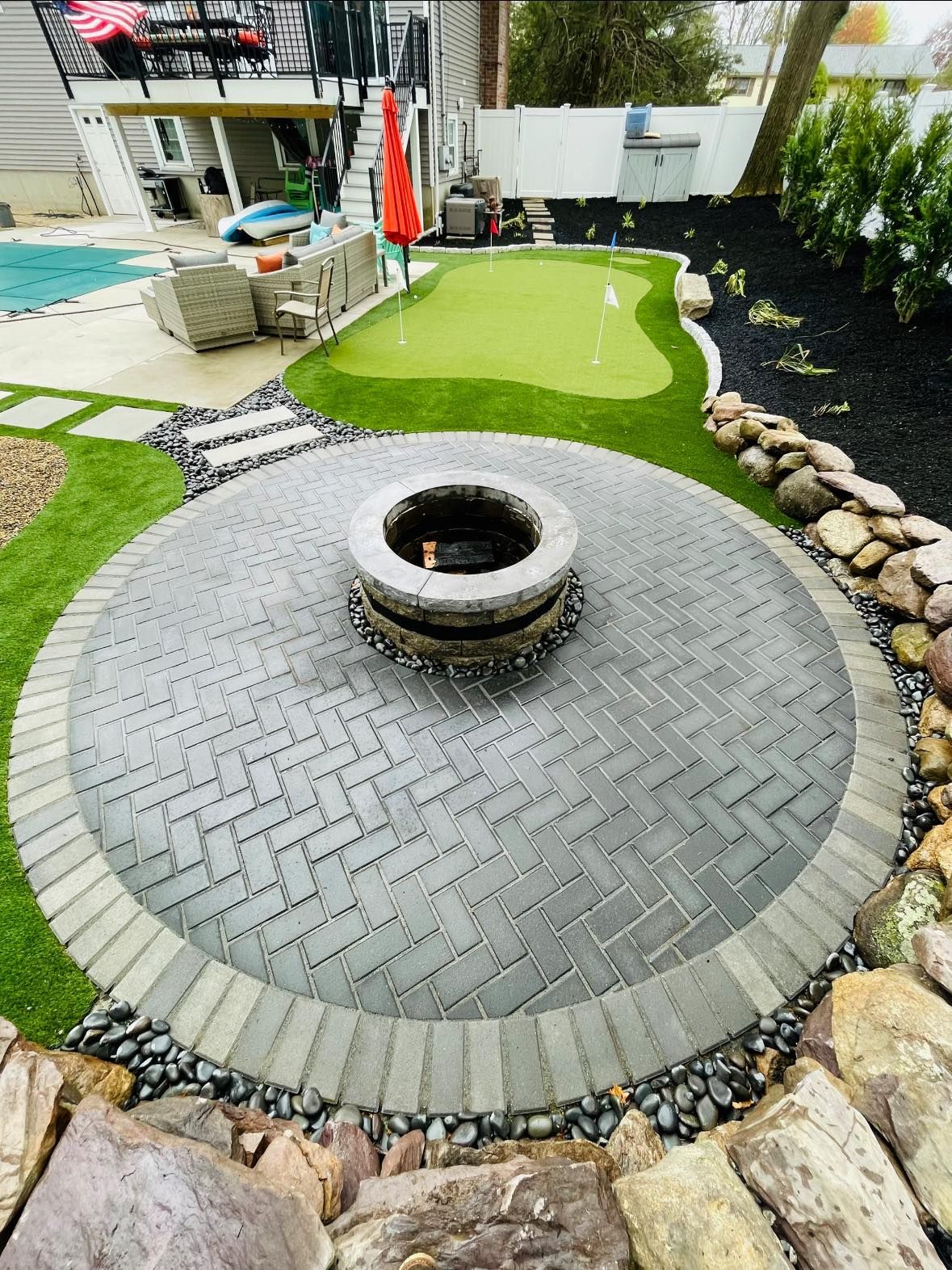 A backyard with a fire pit and a putting green.