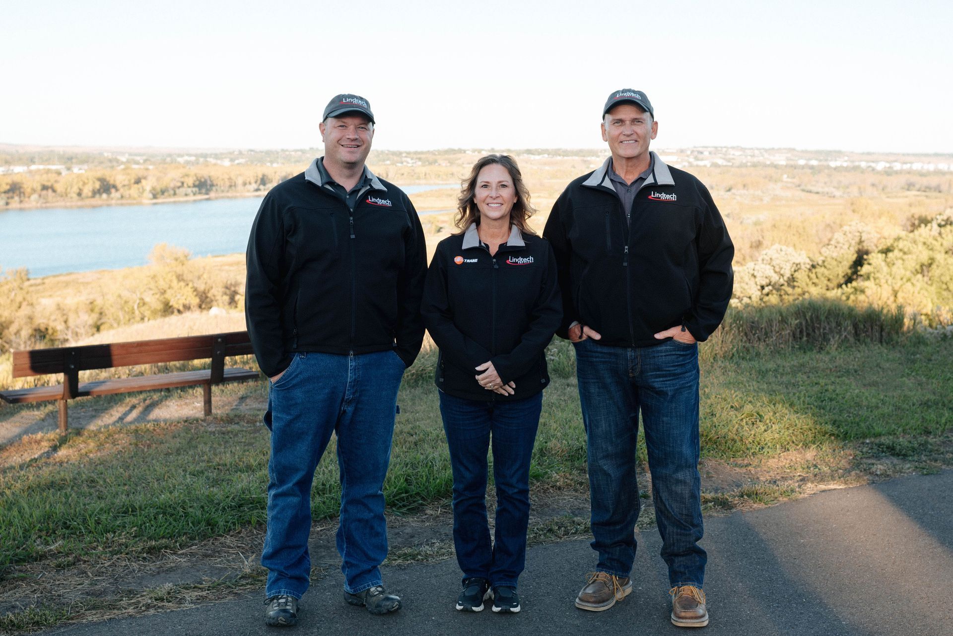Three Lindtech Services, Inc employees are standing side by side in front of a lake.