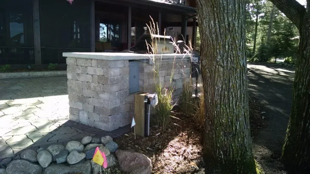 Stone planter and tree beside a building entrance in a shaded outdoor area