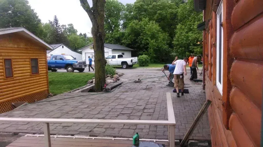 Outdoor campsite with cabins, tents, and people on a paved path beside a log building