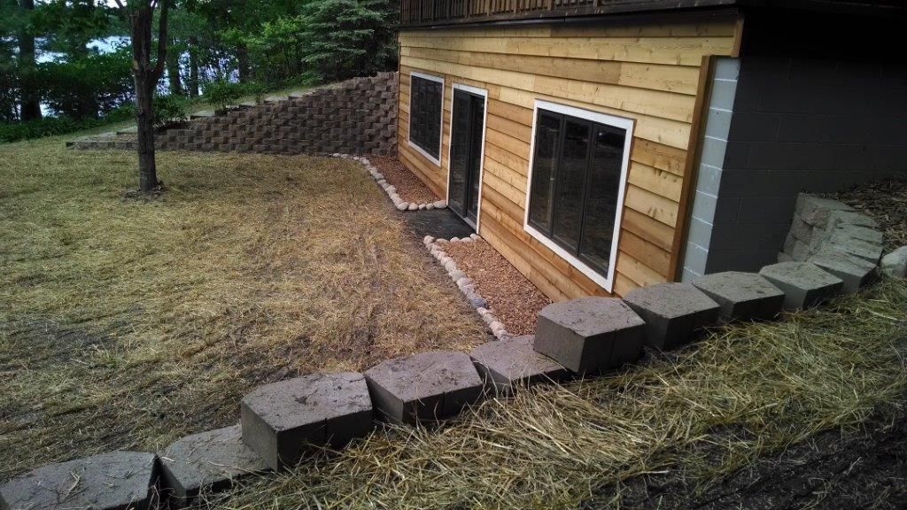 Small wooden shed beside a grassy yard, with steps leading up to two windows.