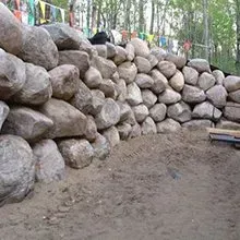 Stacked boulders forming a retaining wall in a wooded outdoor area