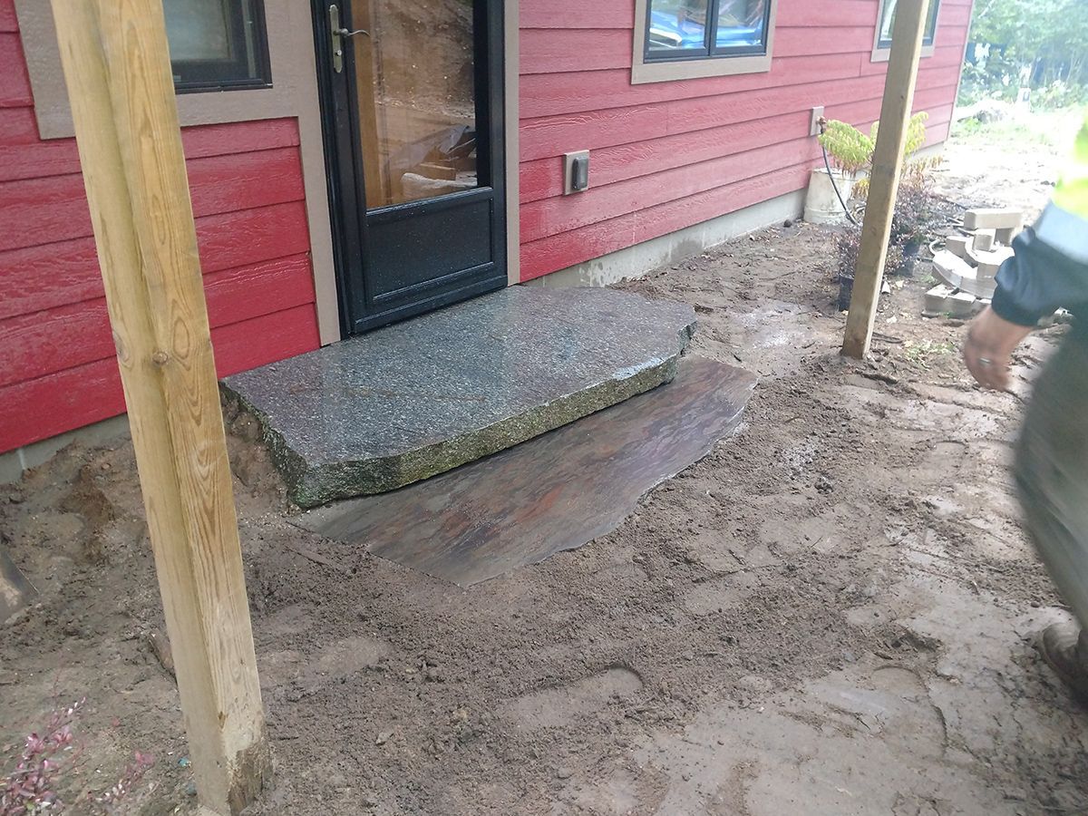 Red house porch with a concrete step and muddy ground, with a person partly visible at right