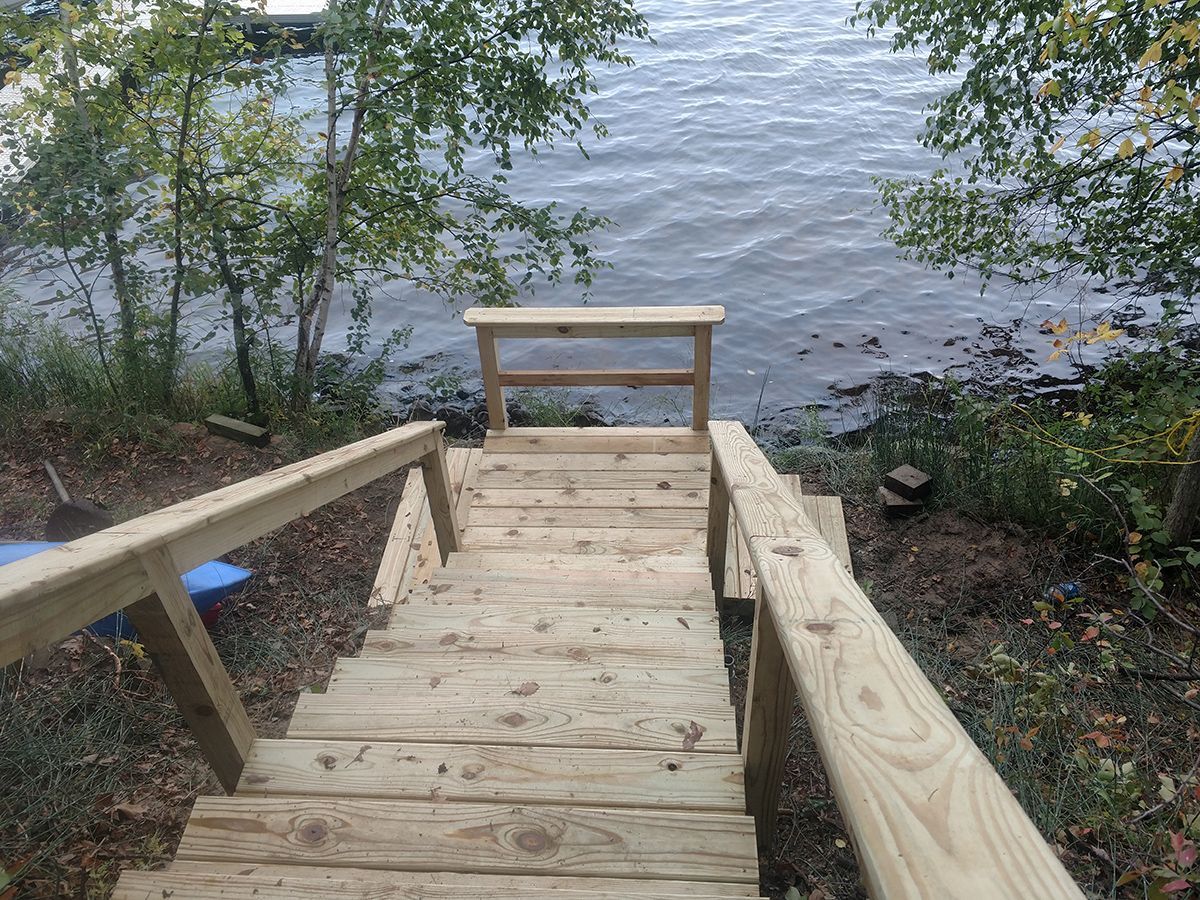Wooden stairs leading down to a lake, with a small bench at the water’s edge.
