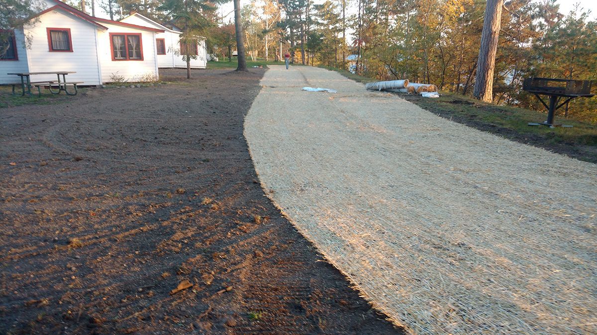 Gravel driveway leading to a white house surrounded by trees in autumn.
