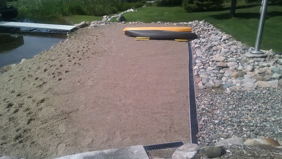 Gravel-covered slope with a small yellow canoe or kayak resting at the top beside a rock-lined edge.
