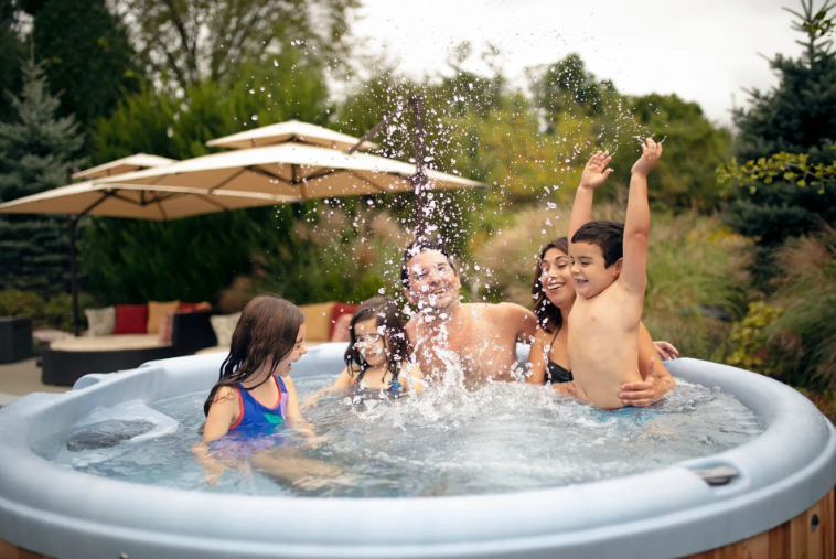 Family splashing in a hot tub outdoors; water sprays.