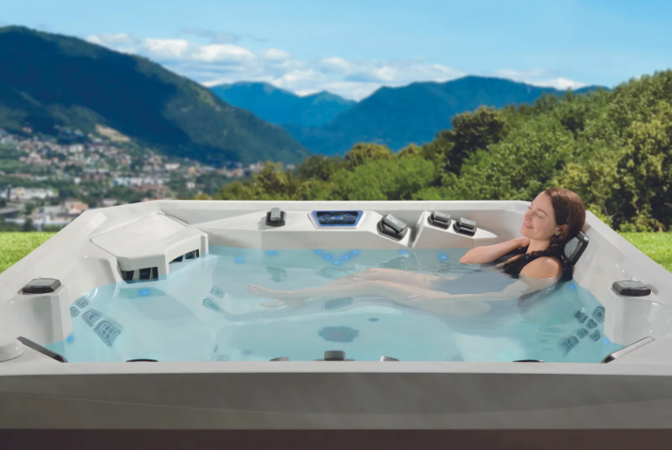 Woman relaxing in a hot tub outdoors with a mountain backdrop.