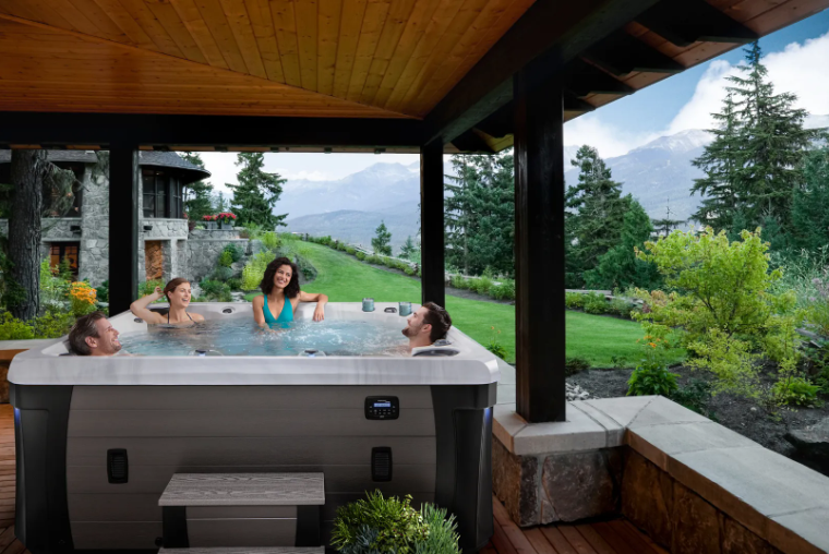 People relaxing in a hot tub on a deck with mountain view.