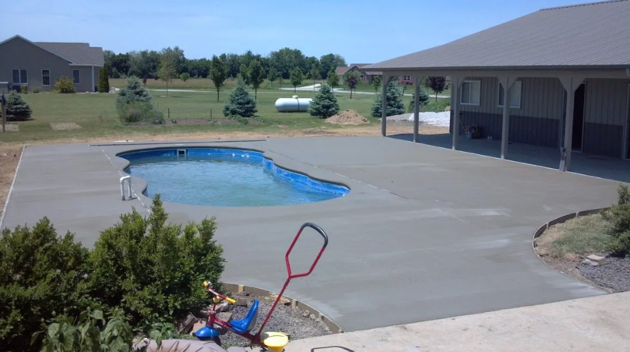 Concrete pool deck with pool and covered patio on a sunny day.