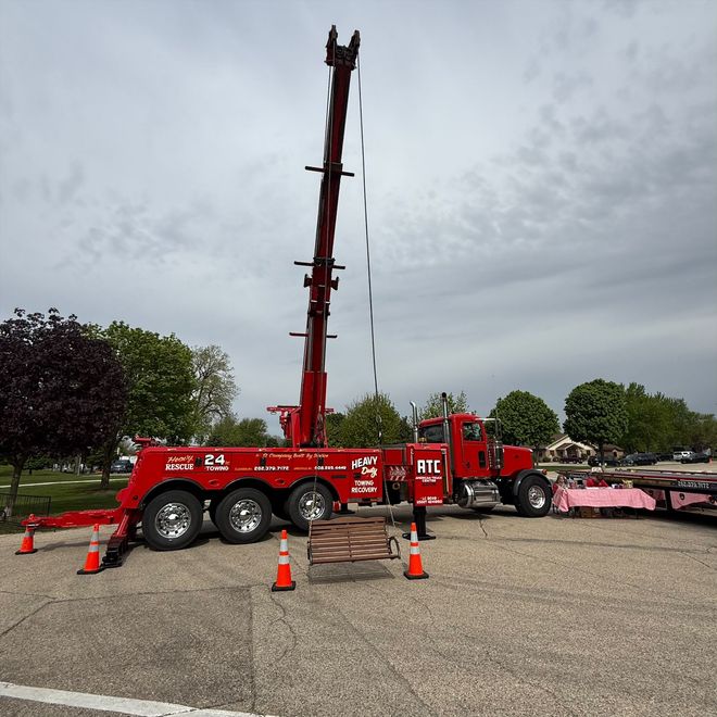 Red mobile drilling rig on a trailer in a parking lot, with orange cones around it.
