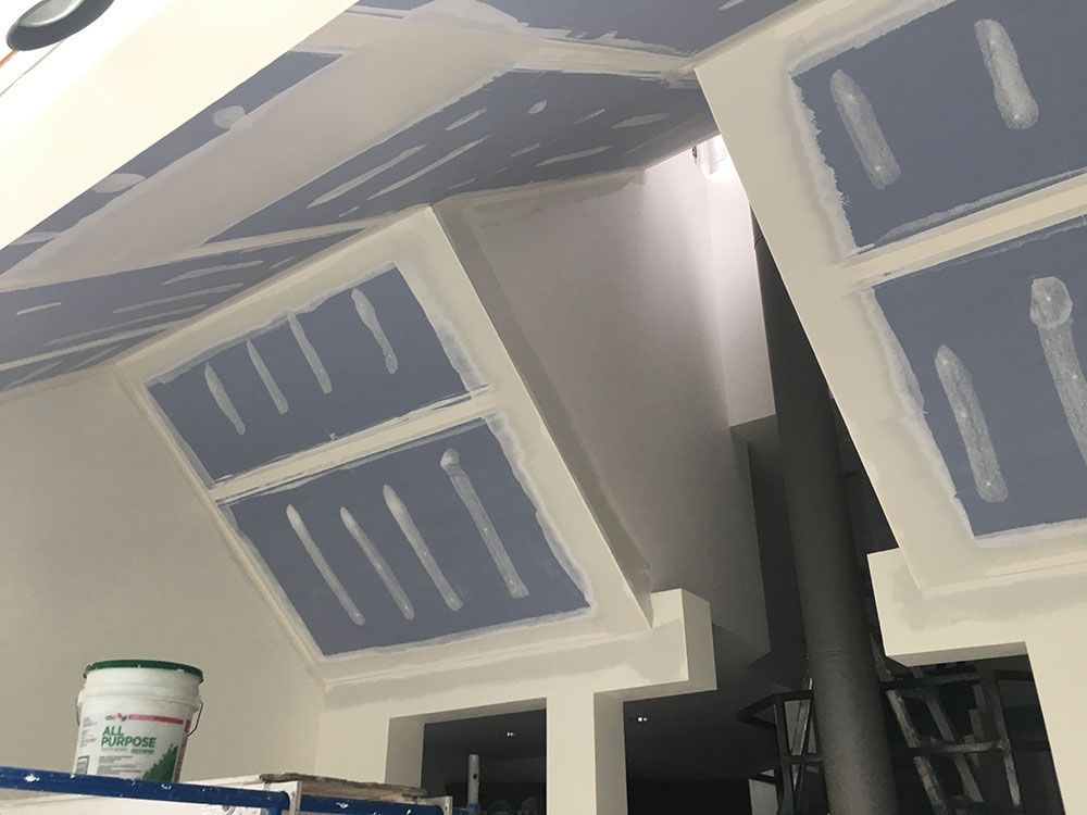 A bucket of paint sits on a shelf in a room under construction