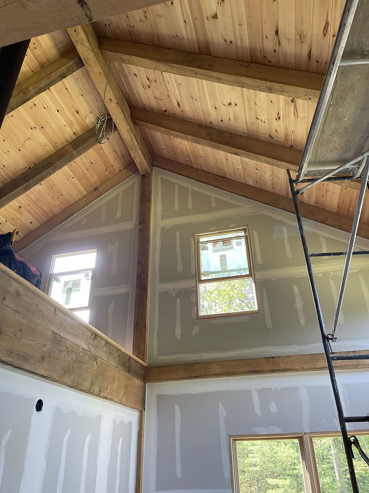 A room with a wooden ceiling and a ladder in it.
