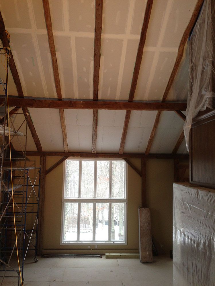 An empty room with a large window and wooden beams