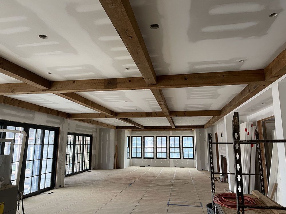 A large room with a lot of windows and wooden beams on the ceiling.