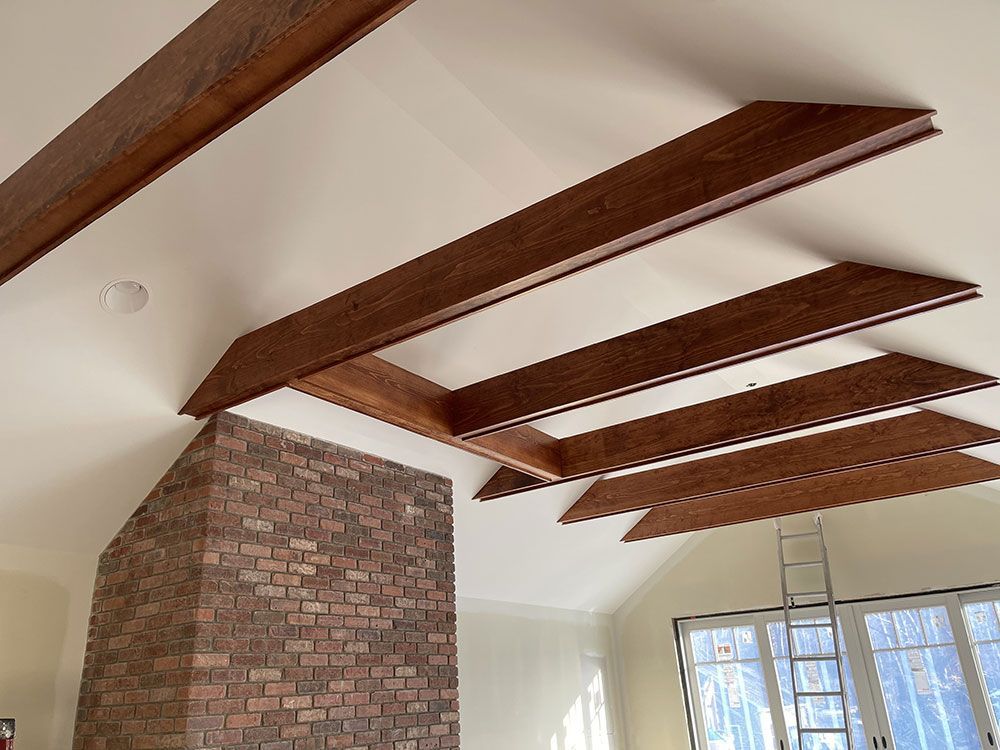 A living room with a brick fireplace and wooden beams on the ceiling.