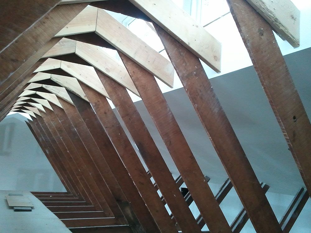 A row of wooden beams are lined up against a white wall