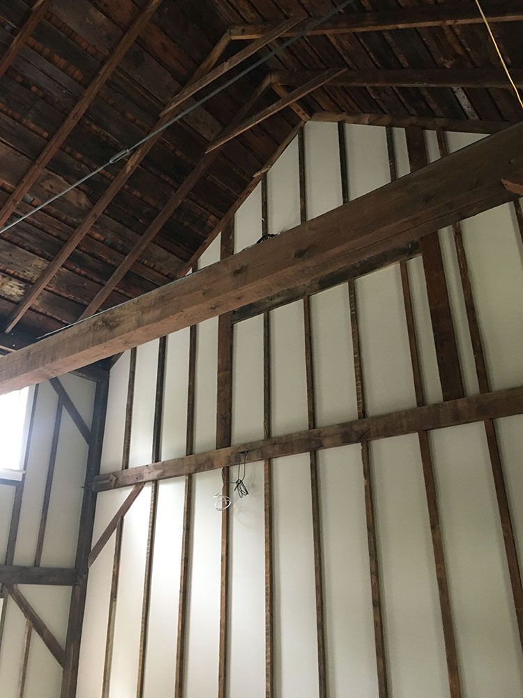 The inside of a barn with wooden beams and white walls.