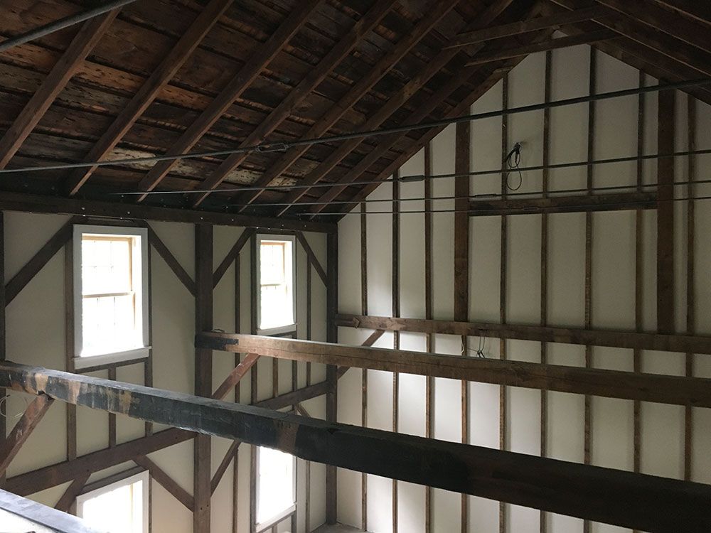 The inside of a barn with wooden beams and white walls.