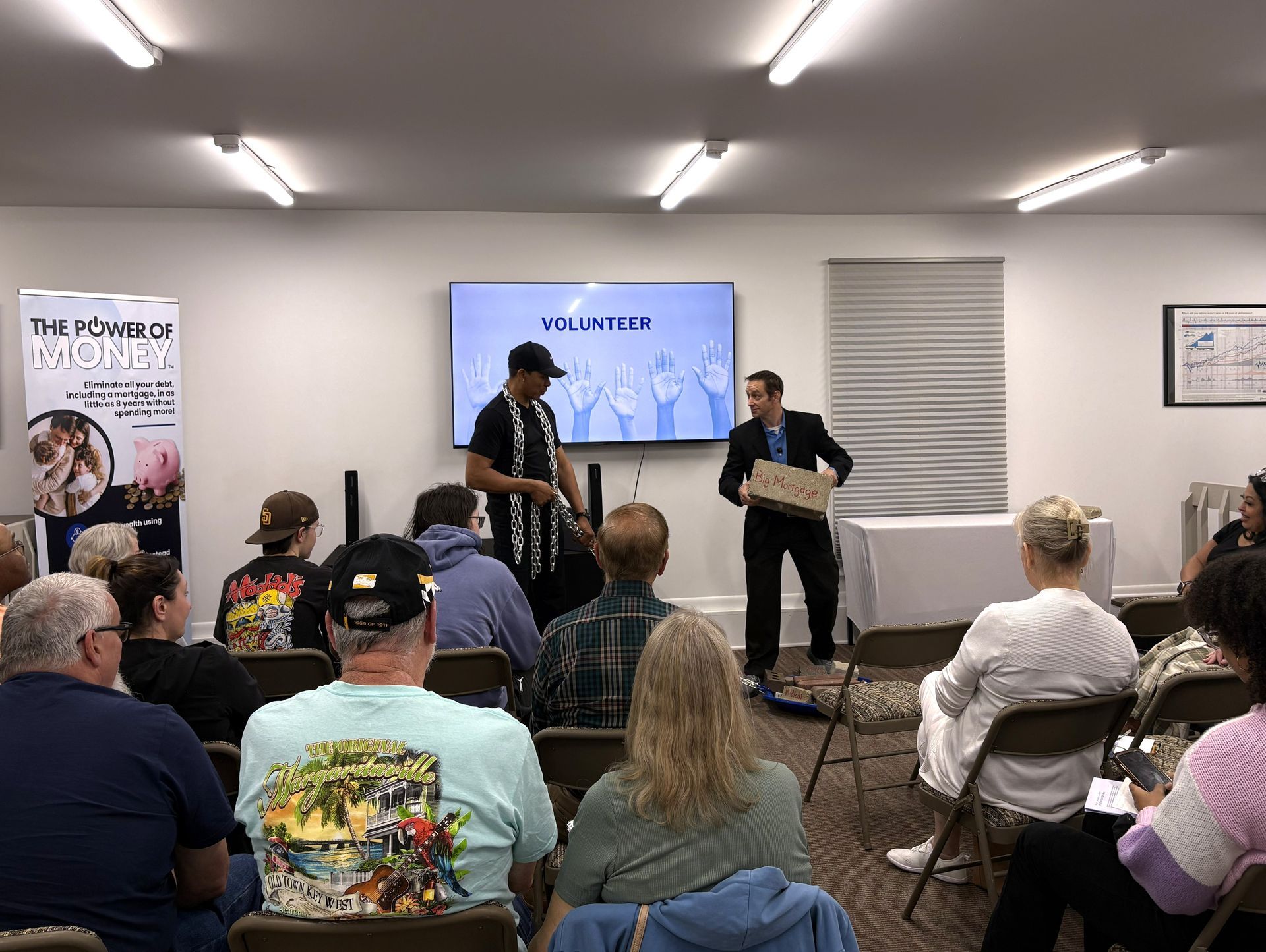 Panel discussion in a small room, with two speakers at the front and an audience seated facing them.