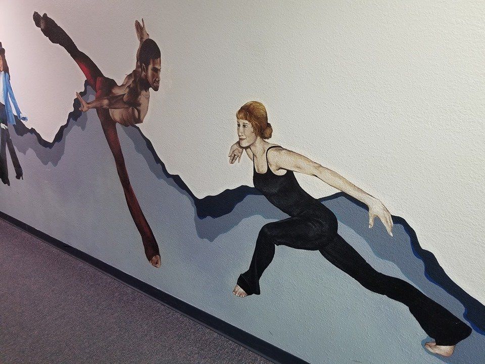 Mural of two dancers leaping across a stylized mountain range; a woman in black reaches forward, a man in red ascends.