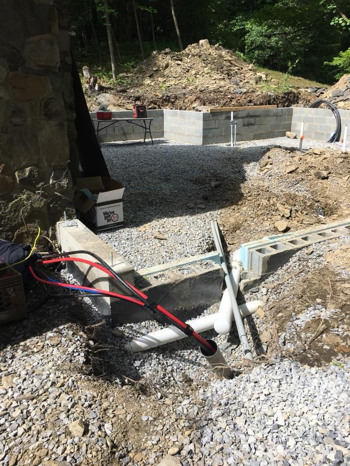 Construction site with pipes and wires in the foreground; concrete foundation blocks in the background.