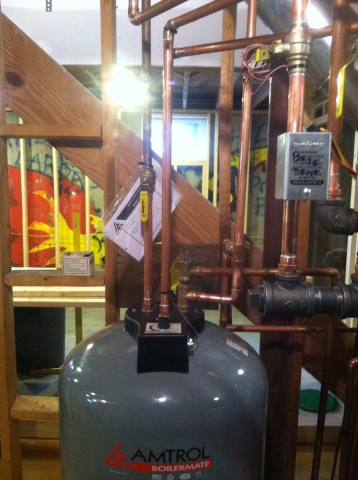 Copper pipes and tank system in a utility room setting.