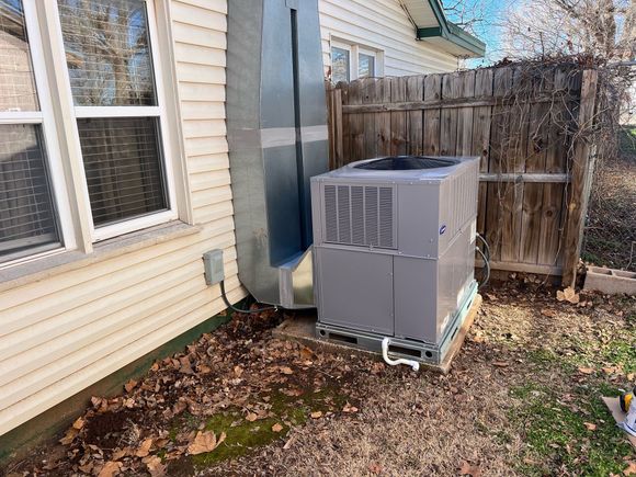an air conditioner is sitting on the side of a house next to a window .