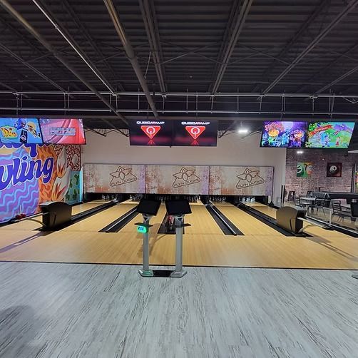 A bowling alley with a lot of televisions on the wall.
