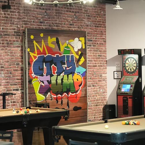 A pool table in a room with graffiti on the wall that says city jump