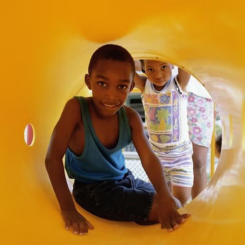 A boy and a girl are playing in a yellow tunnel