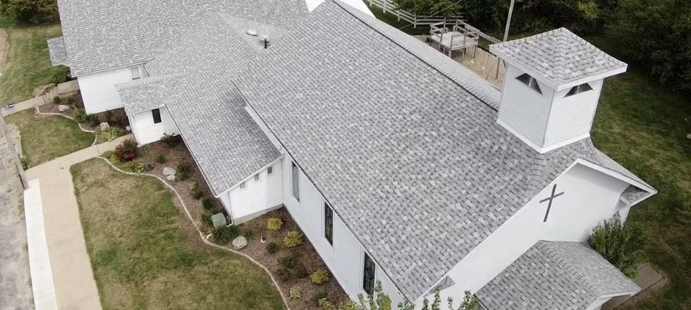 An aerial view of a church with a gray shingle roof.