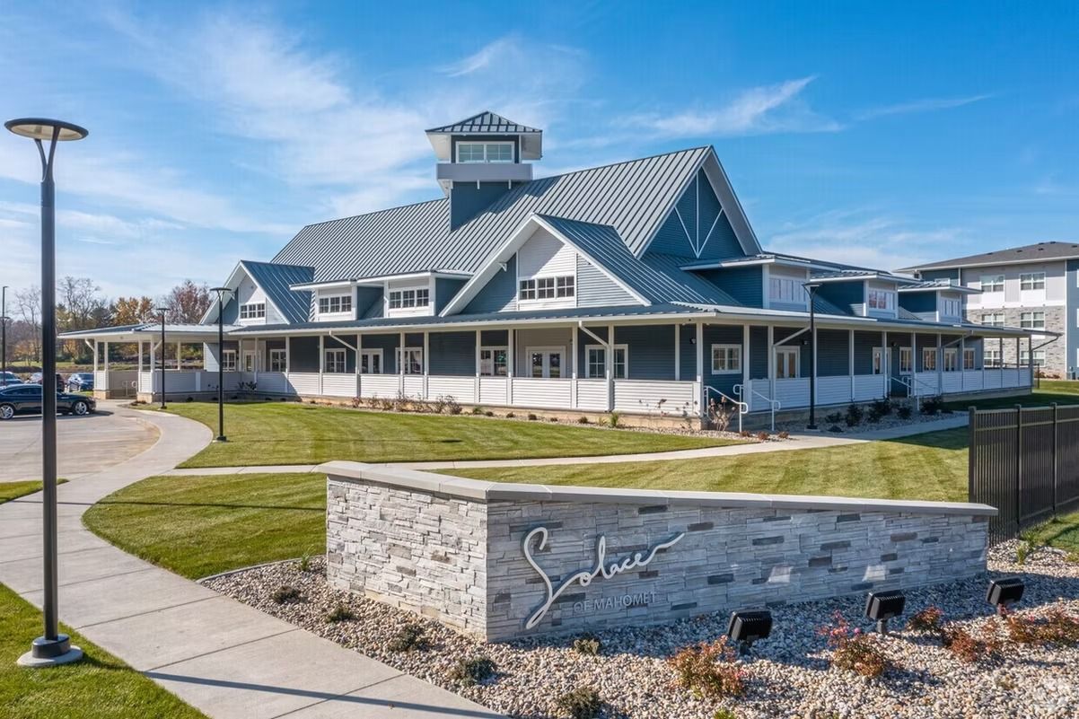 A large house with a sign in front of it and a walkway leading to it.