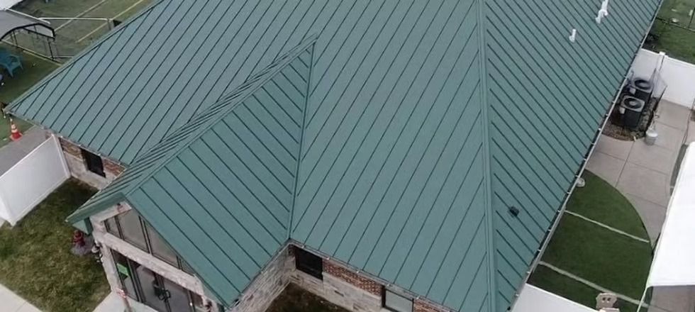 An aerial view of a house with a green metal roof.