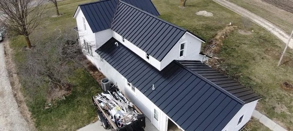 An aerial view of a white house with a black roof.