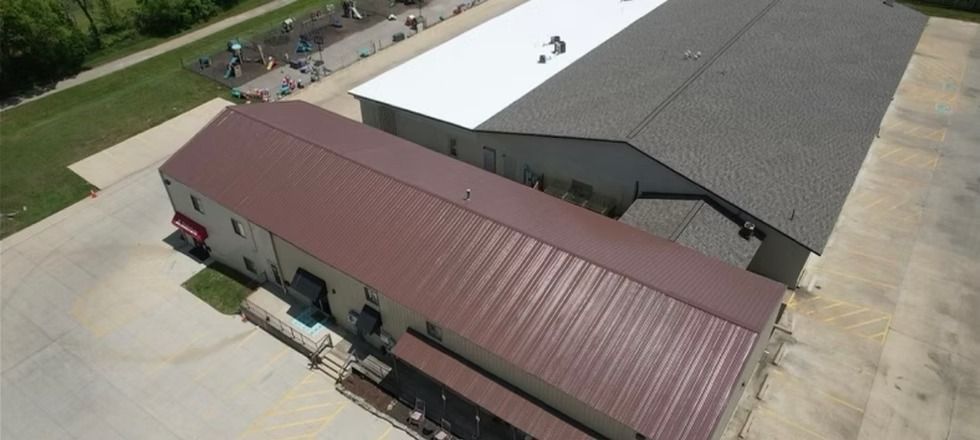 An aerial view of a building with a brown roof and a white roof.