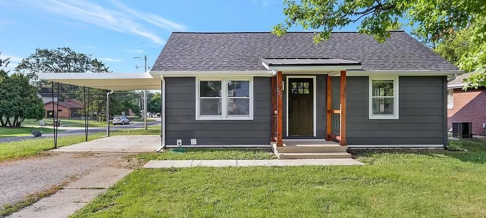 A small house with a carport in front of it is for sale.