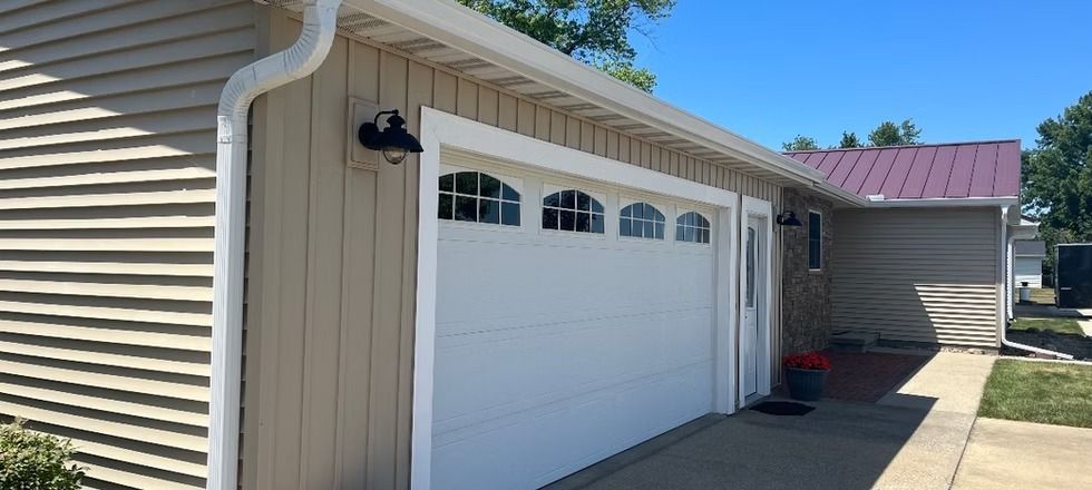 A white garage door is sitting next to a house.
