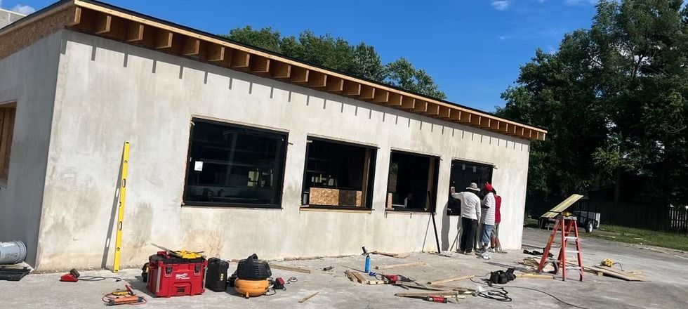 A group of people are standing in front of a building under construction.