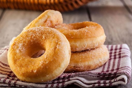 Sugar-coated donuts stacked on a plaid cloth napkin