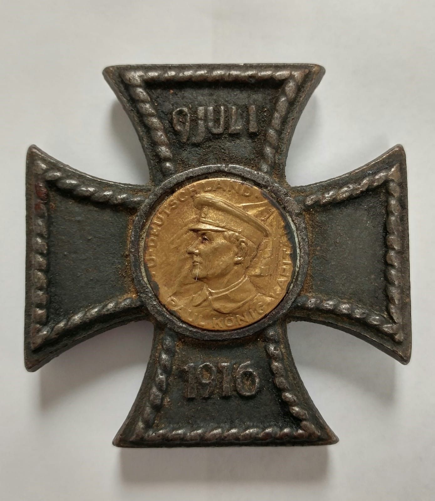 A cross with a coin in the center and the date 1910