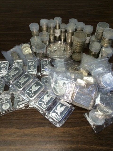 A pile of silver bars and coins on a table