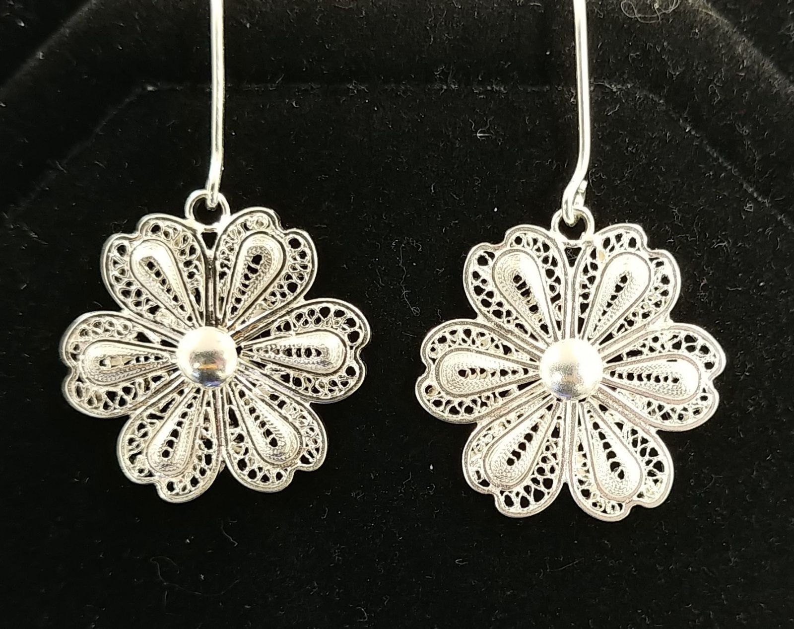 A pair of silver earrings with flowers on them