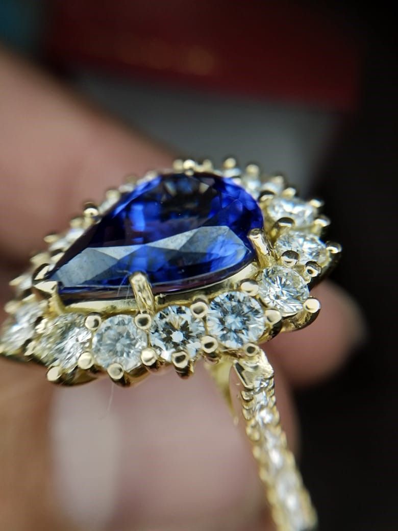A person is holding a sapphire and diamond ring in their hand.
