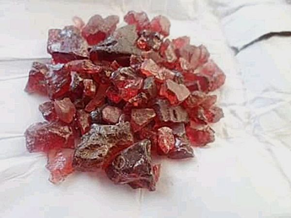 A pile of red rocks on a white surface.