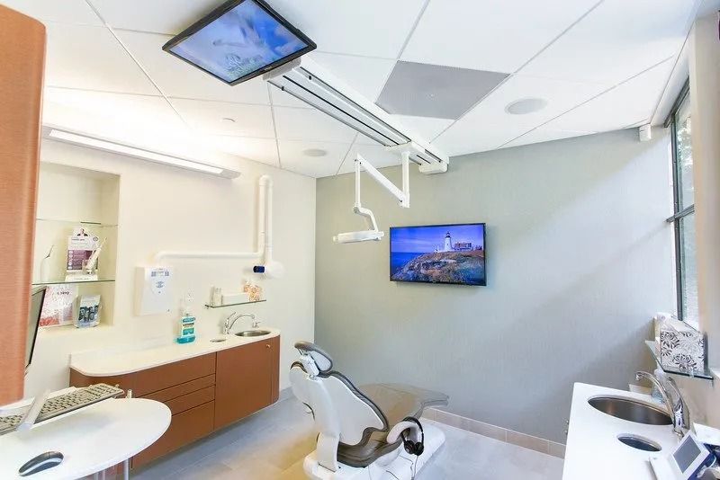 A dental office with a dental chair and a television on the wall.